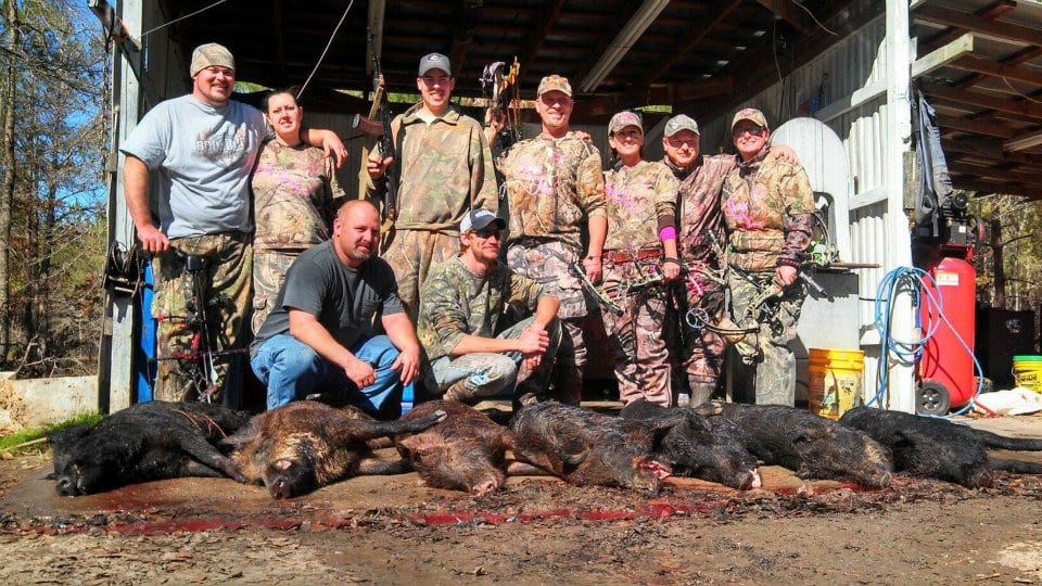 A group of hunters poses with several harvested wild boars.