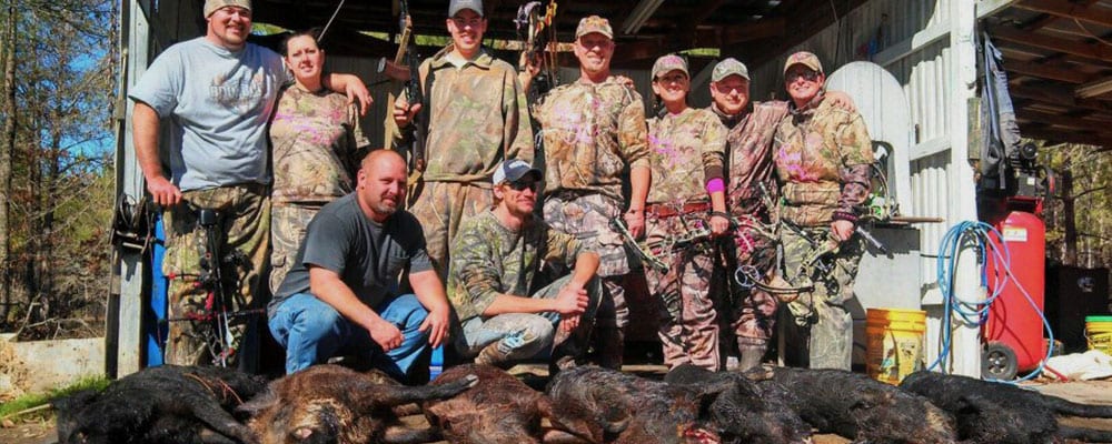 A group of hunters poses with several harvested wild boars.