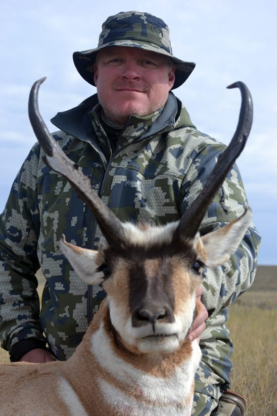 A hunter in camouflage poses with a harvested pronghorn.