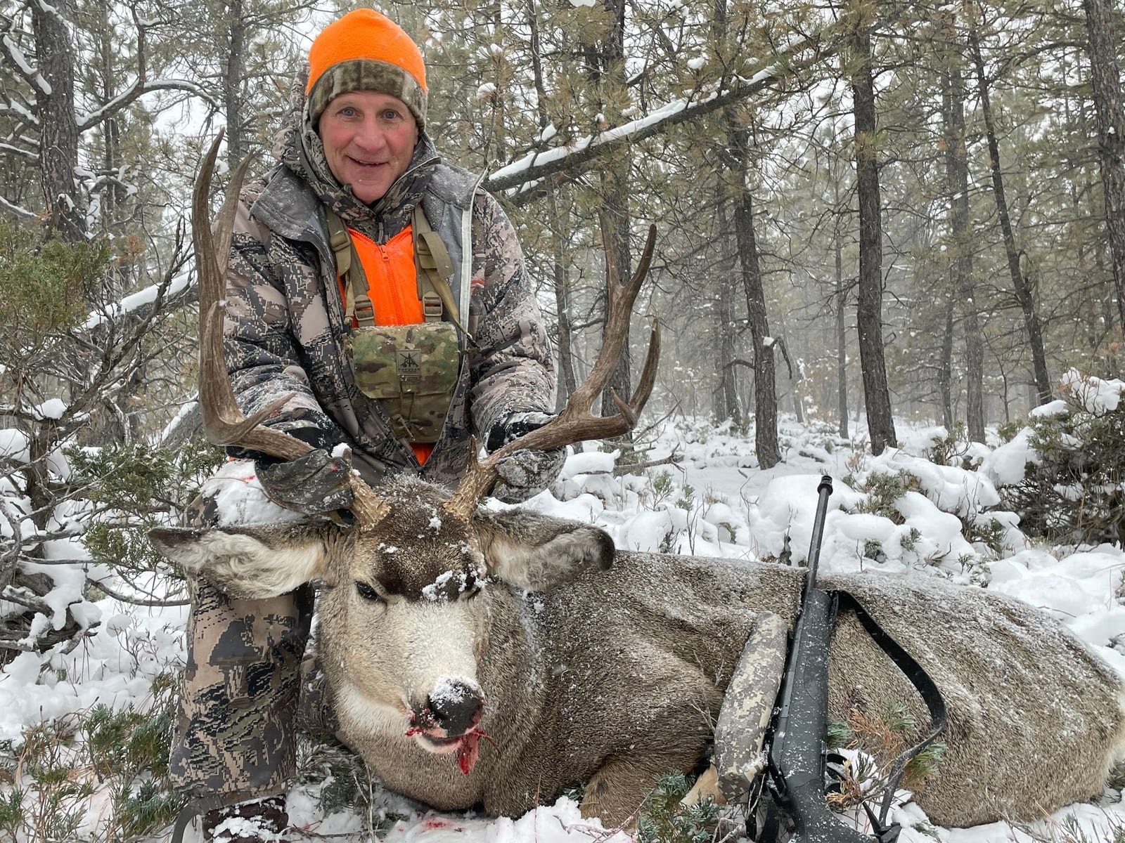 Man posing with deer in a forest