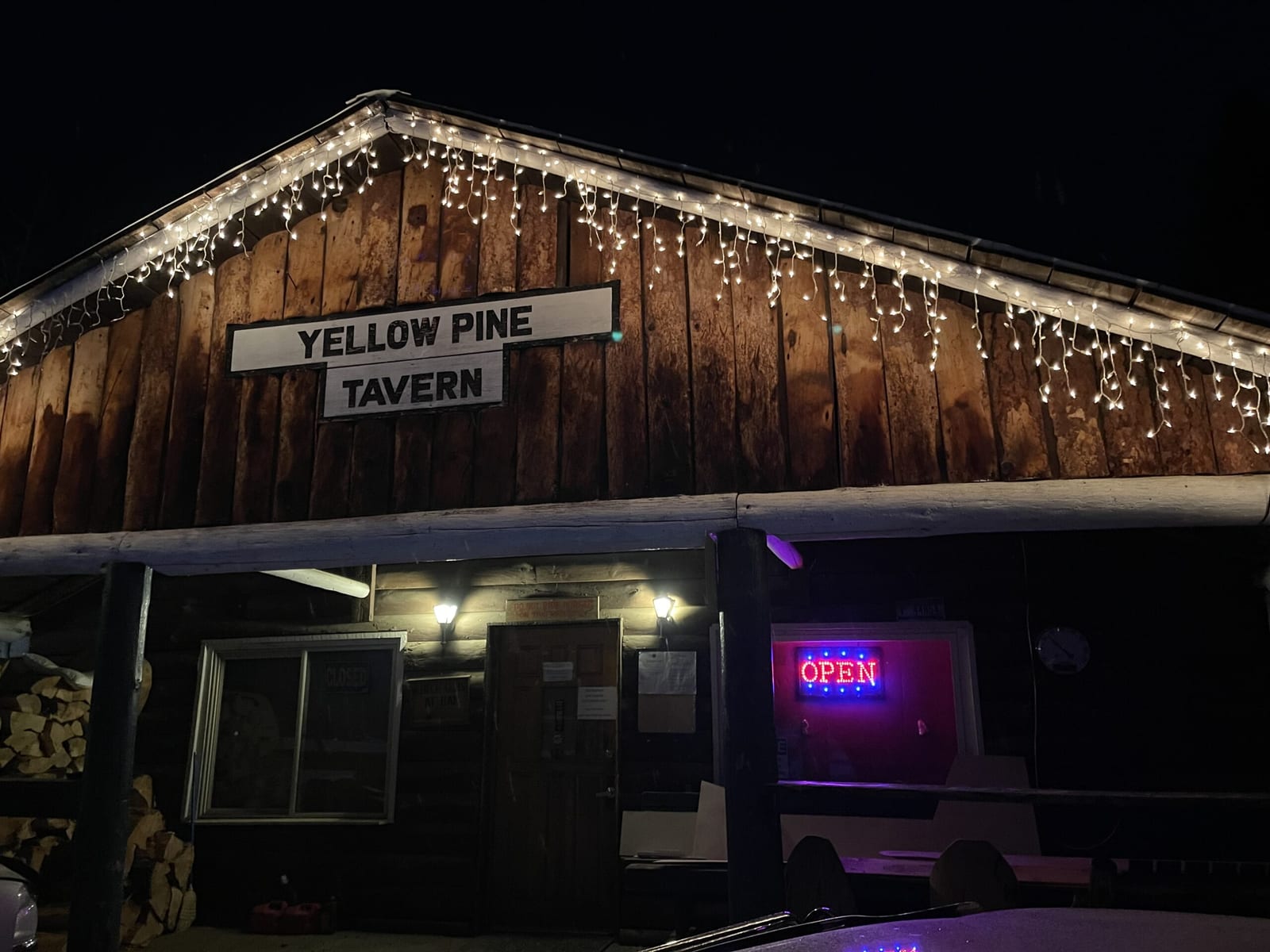 The Yellow Pine Tavern building at night, decorated with string lights.