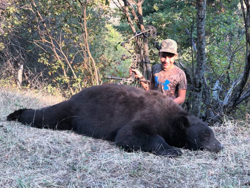A young hunter poses with a harvested black bear.