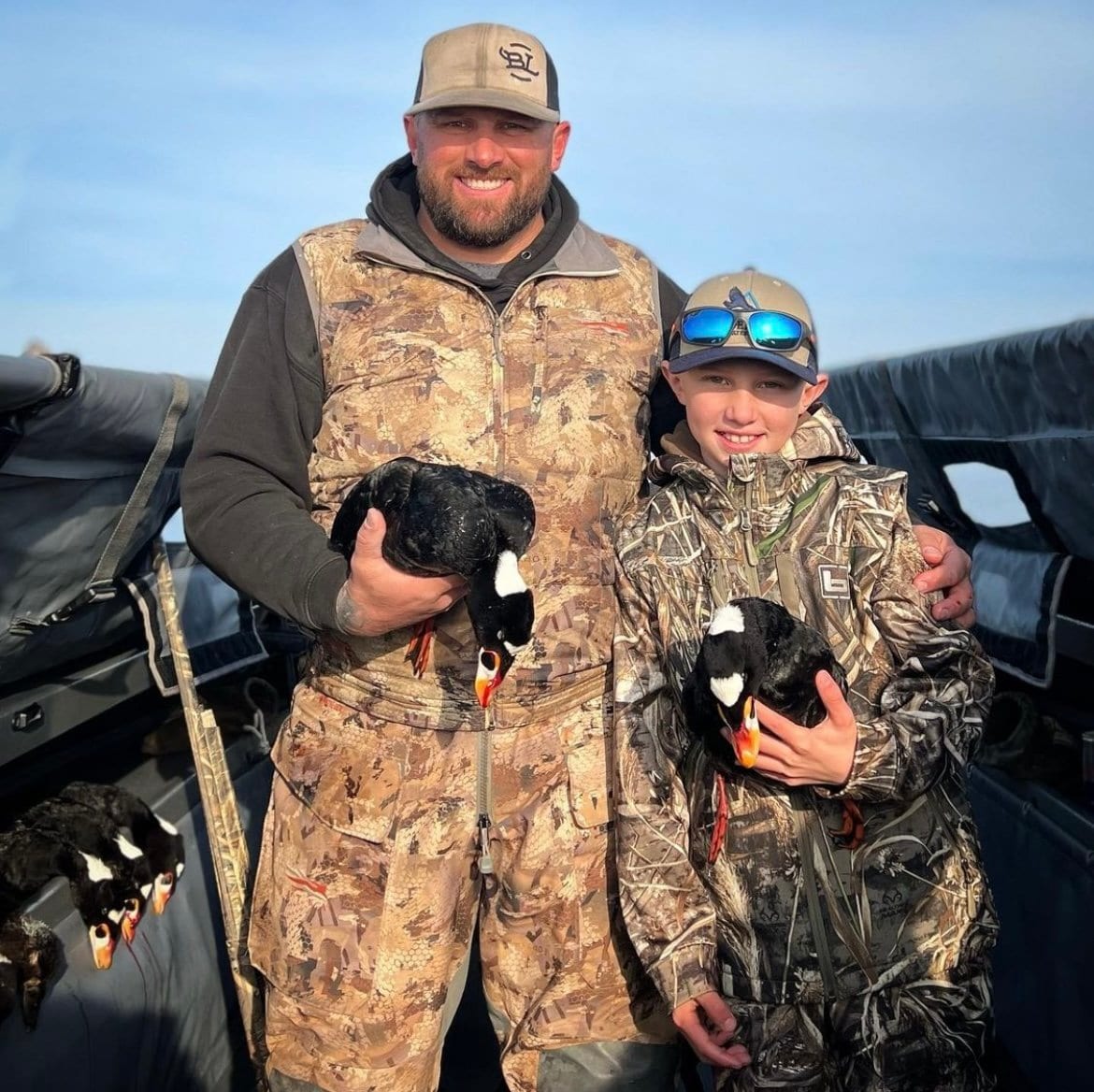 An adult and a child hunter pose with harvested scoter ducks.