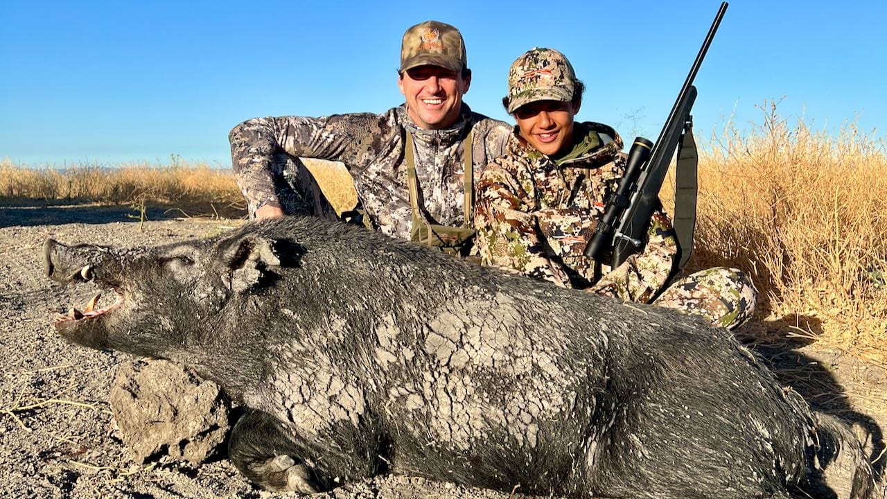 Two hunters pose with a harvested wild boar.