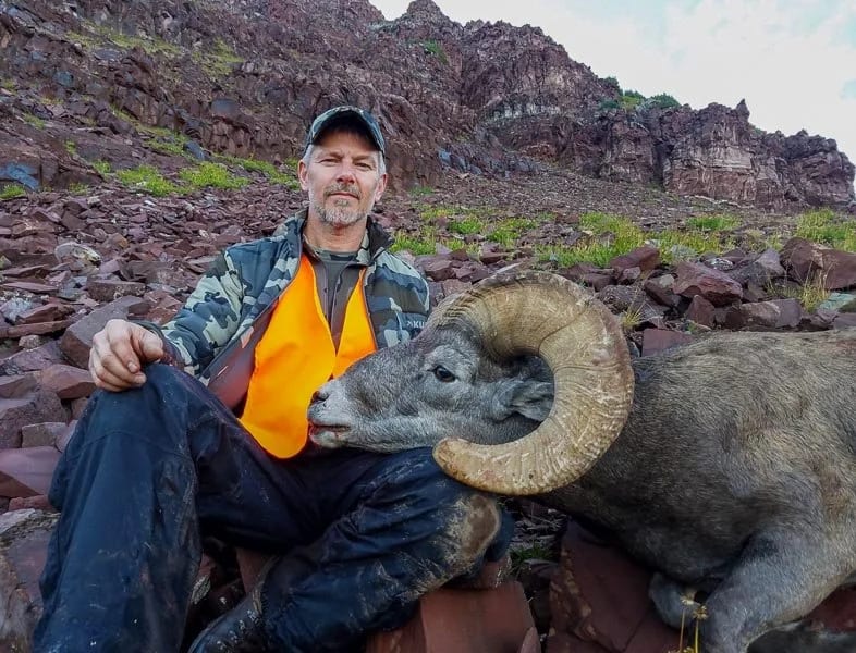 Hunter with trophy bighorn sheep ram harvested on a guided hunt in Colorado's rugged unit S13