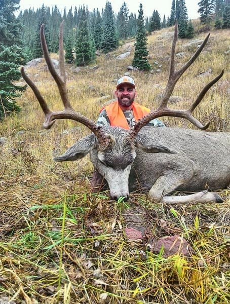 Hunter with trophy mule deer buck harvested on a guided horseback hunt in Colorado's unit 43