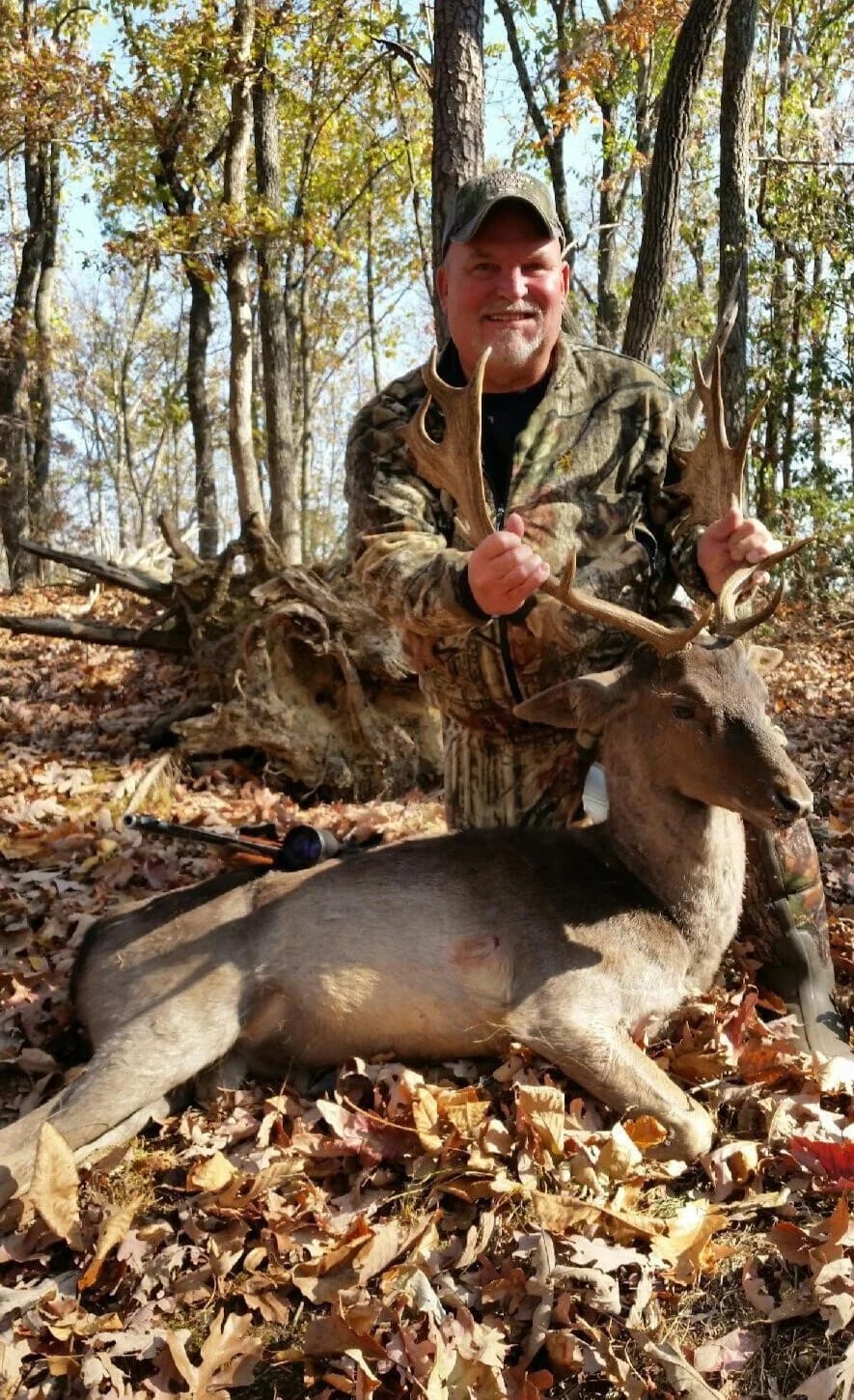 Hunter with a fallow buck taken in the fall woods