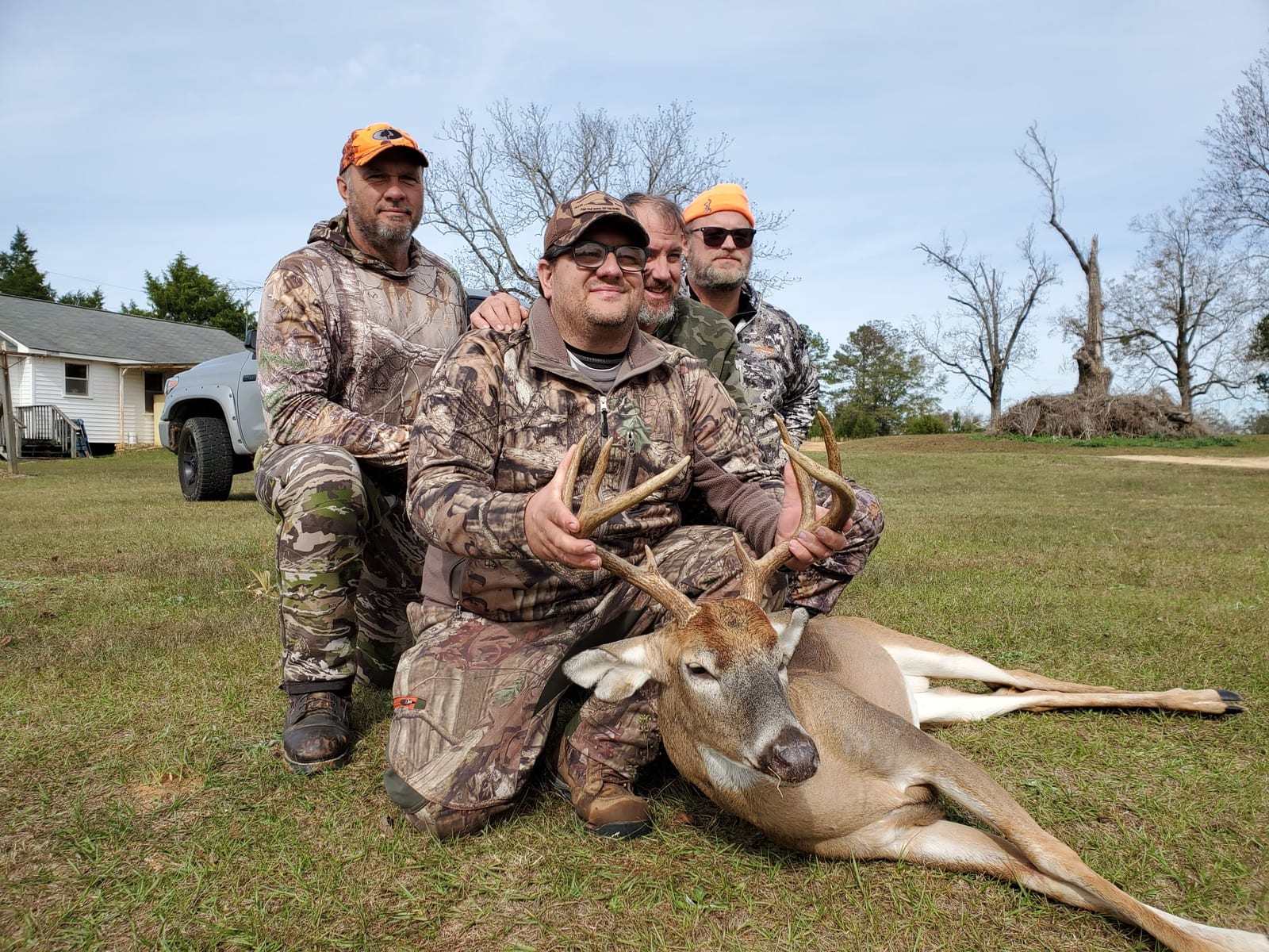 Four hunters pose with a harvested whitetail deer.