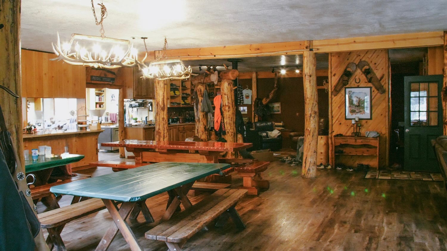 An interior view of a rustic lodge with wooden tables and antler chandeliers.