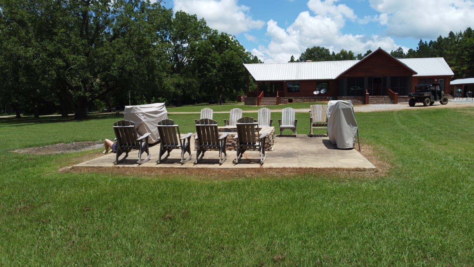 A lodge building with a white roof and a large outdoor patio with chairs and a fire pit.