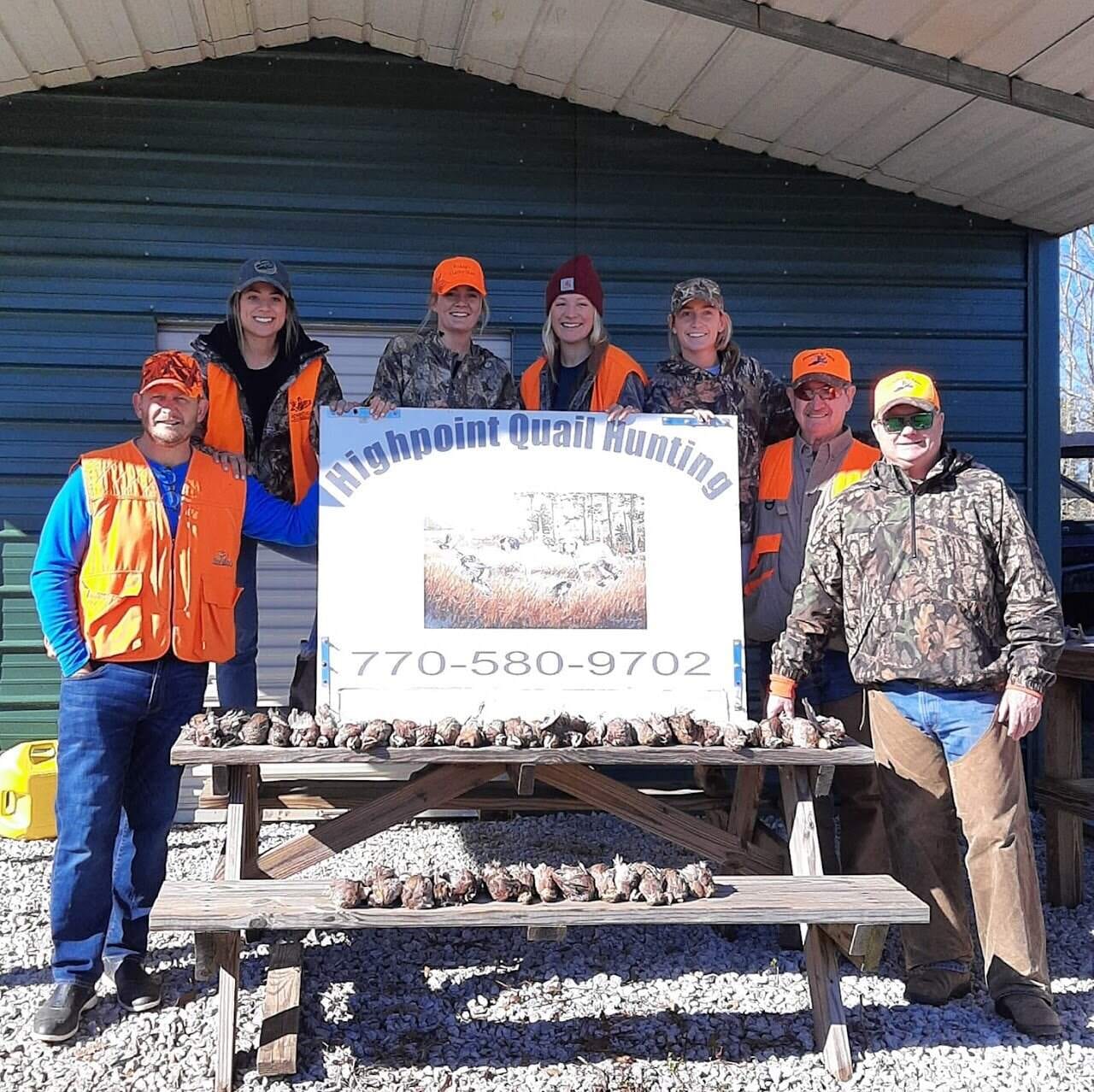 A group of hunters posing behind the Highpoint Quail Hunting sign with their harvested quail