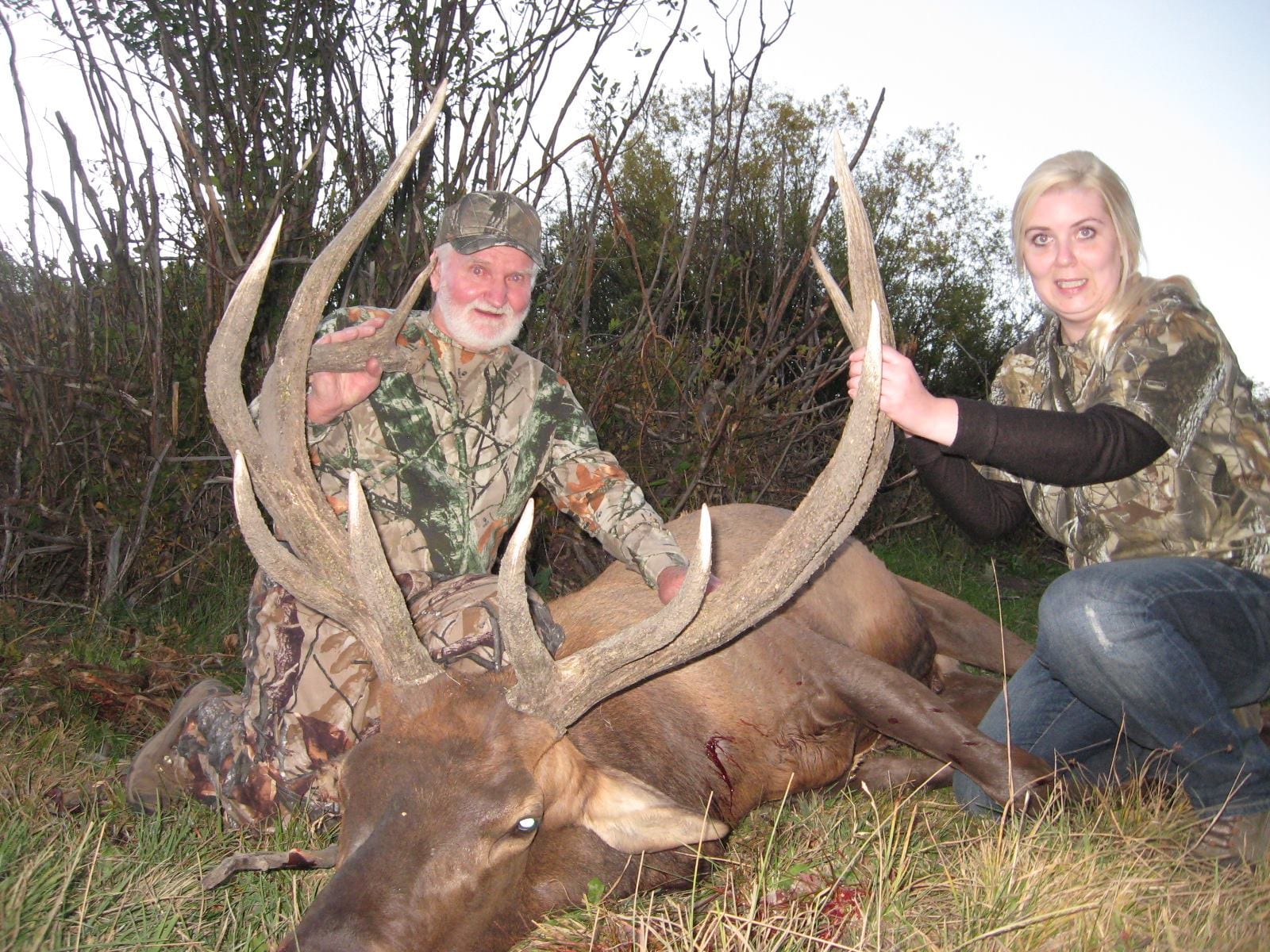 A man and a woman pose with a harvested elk.