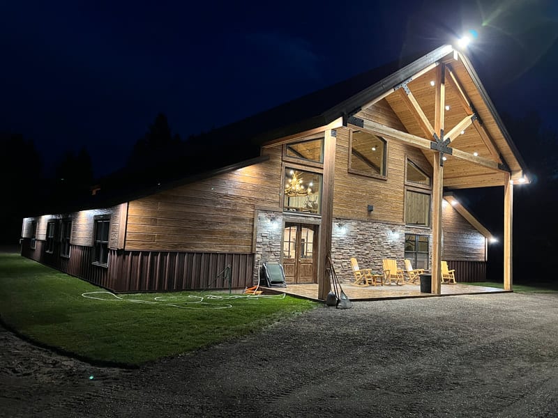 A large wooden lodge with stone accents and a covered porch is illuminated at night.