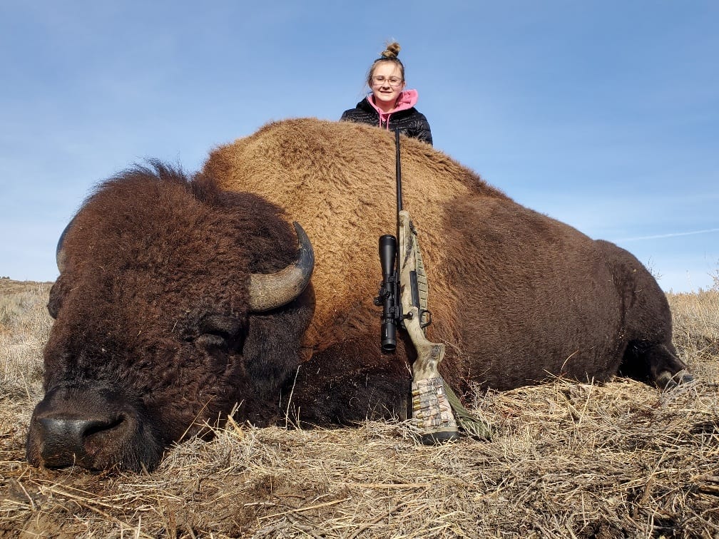 A hunter poses with a harvested bison.
