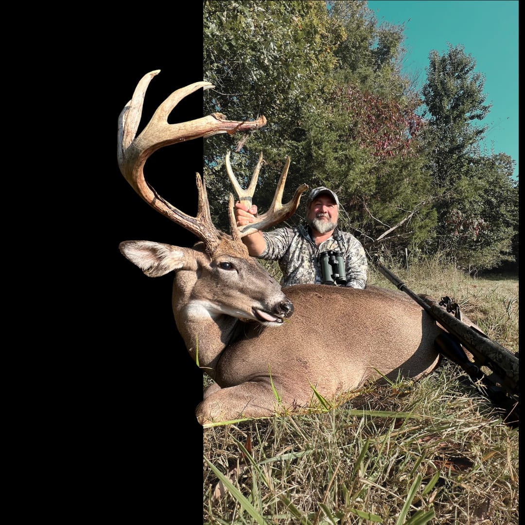 hunter poses with a trophy buck in the field