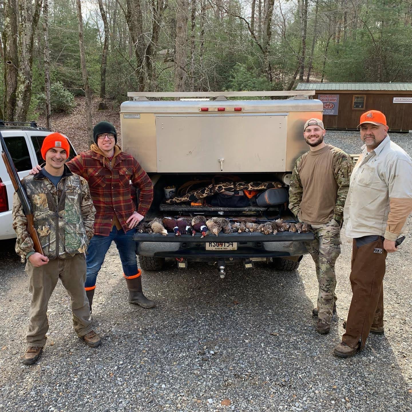 Four men pose with harvested birds in the back of a pickup truck.