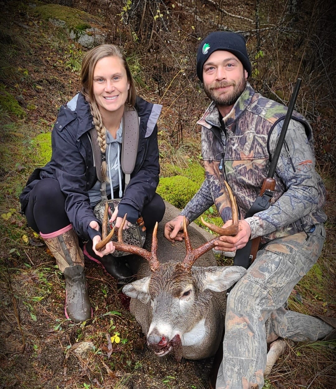 A man and a woman pose with a harvested whitetail deer.