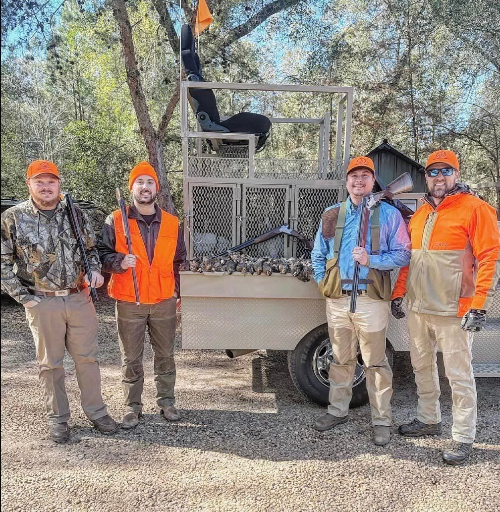 Four men pose with harvested northern bobwhite quail on a trailer.