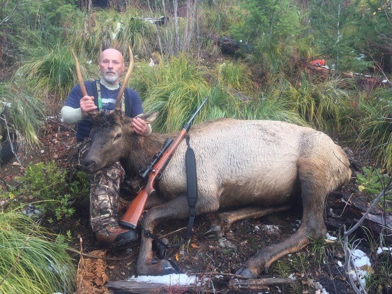 A man holding two guns next to an animal.