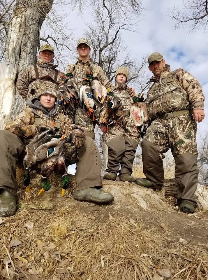 A group of five clients wearing camouflage and showing off their ducks
