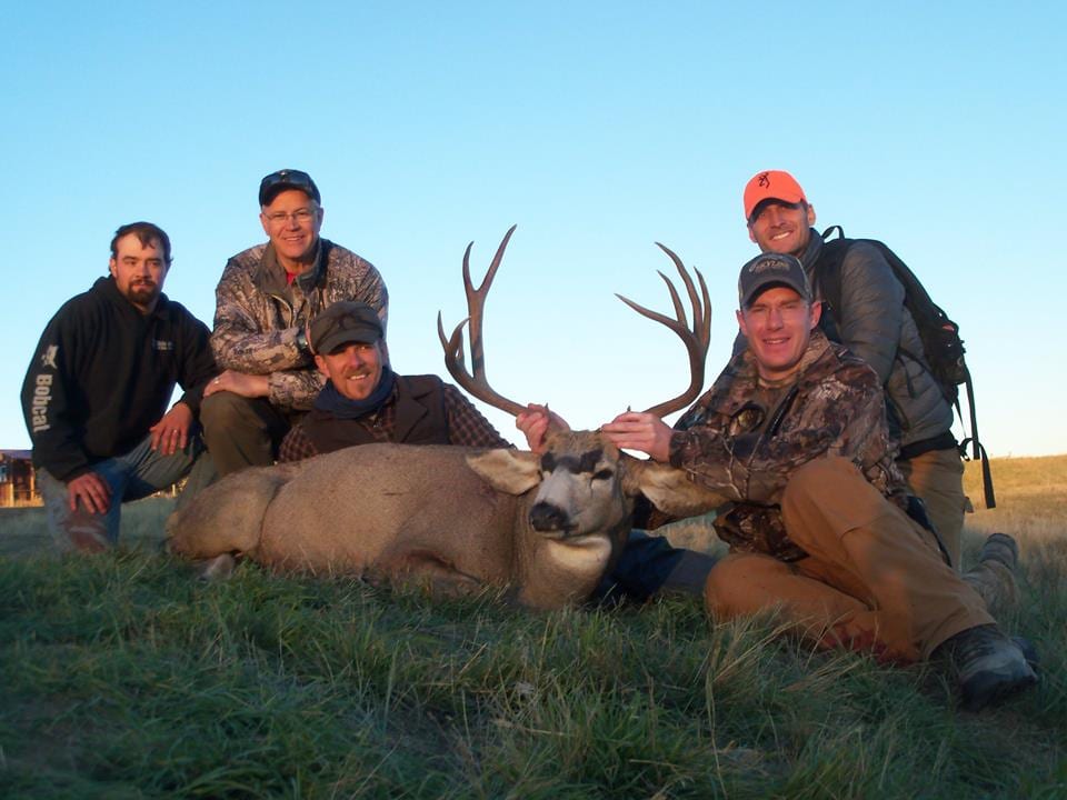 Several hunters pose with a harvested mule deer.