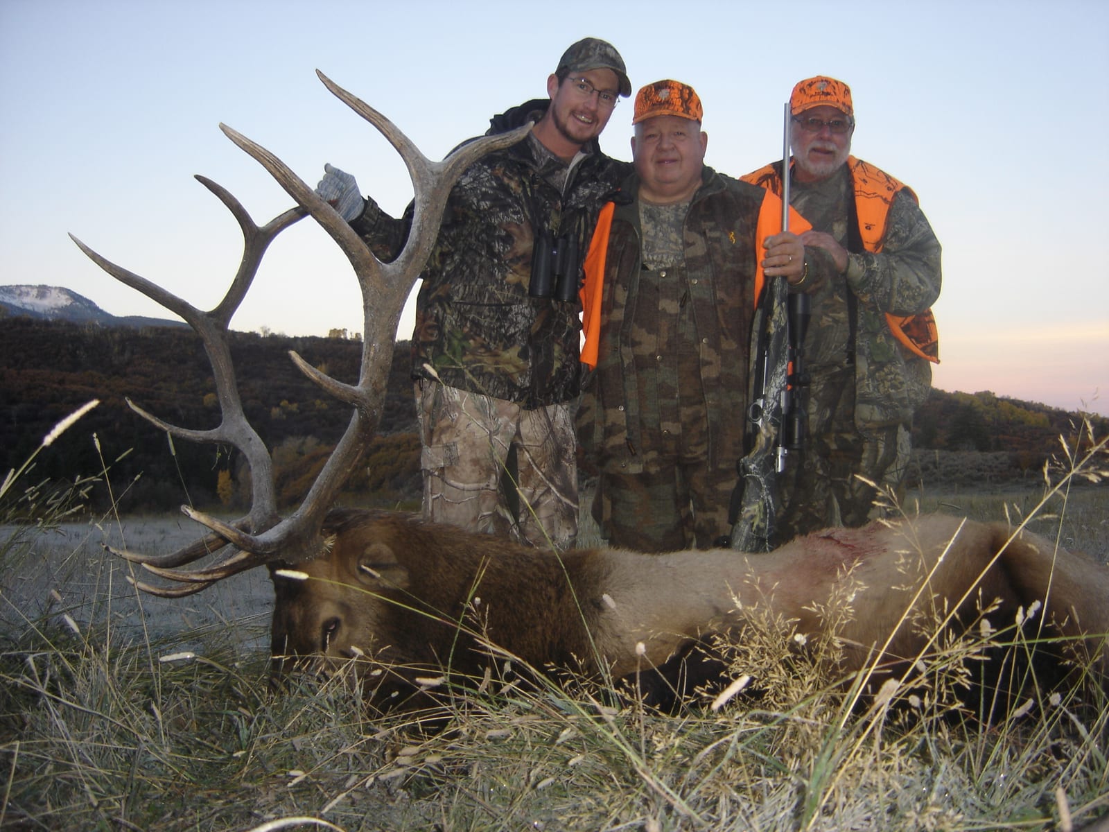 Three hunters pose with a harvested elk.