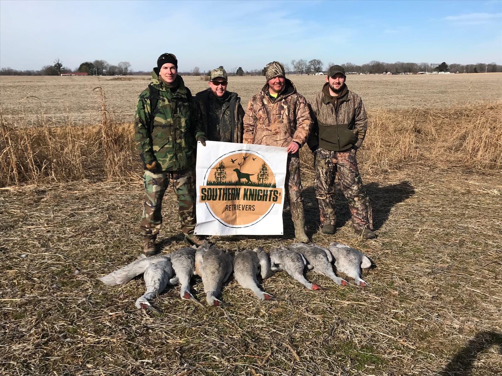Four hunters pose with their harvested geese and a "Southern Knights Retrievers" banner in a field.