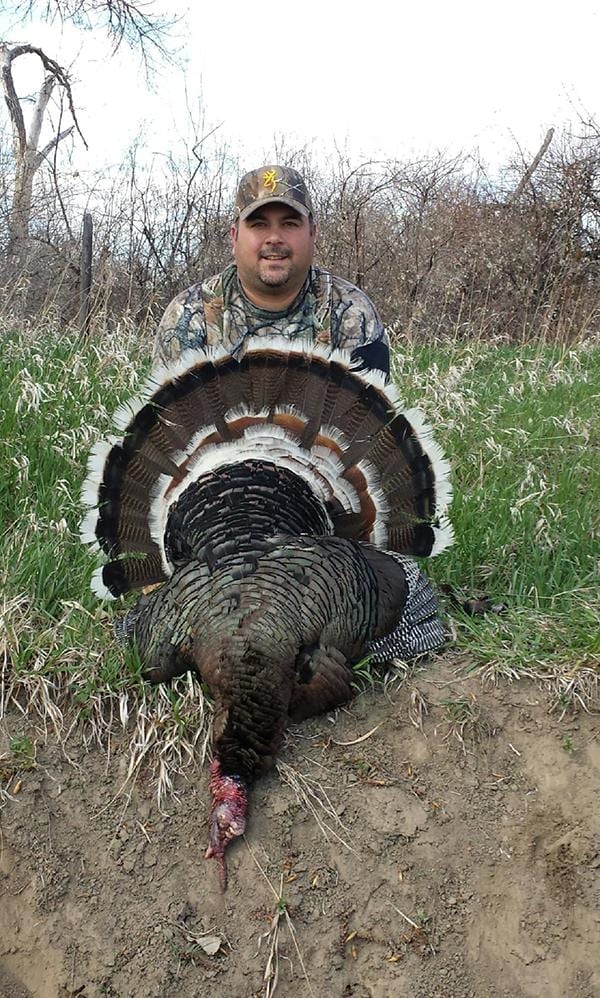 A hunter poses with a harvested wild turkey.