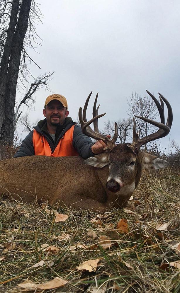 A hunter poses with a harvested whitetail deer.