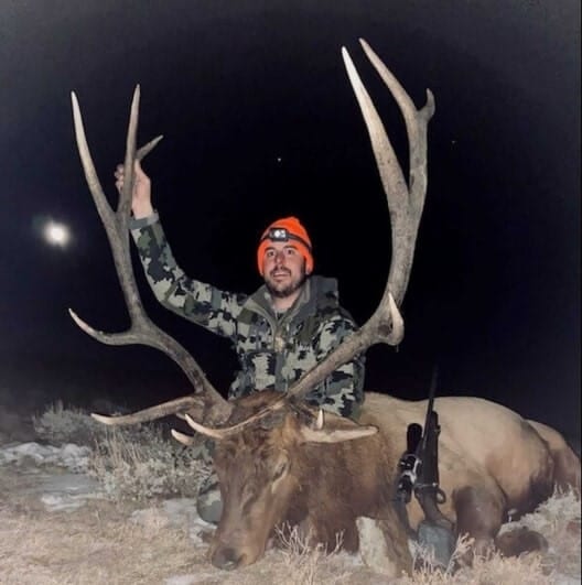A hunter poses at night with a harvested elk.