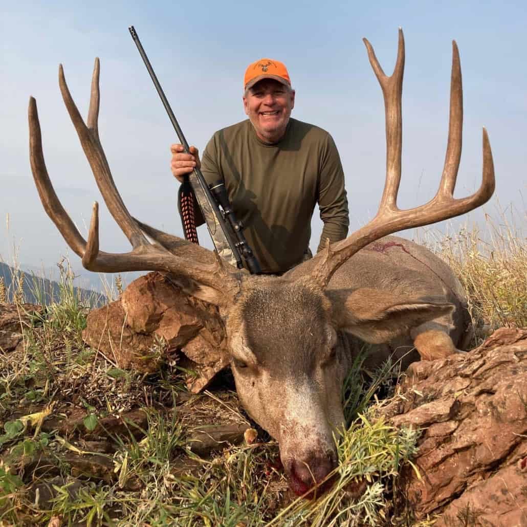 A hunter poses with a harvested mule deer.