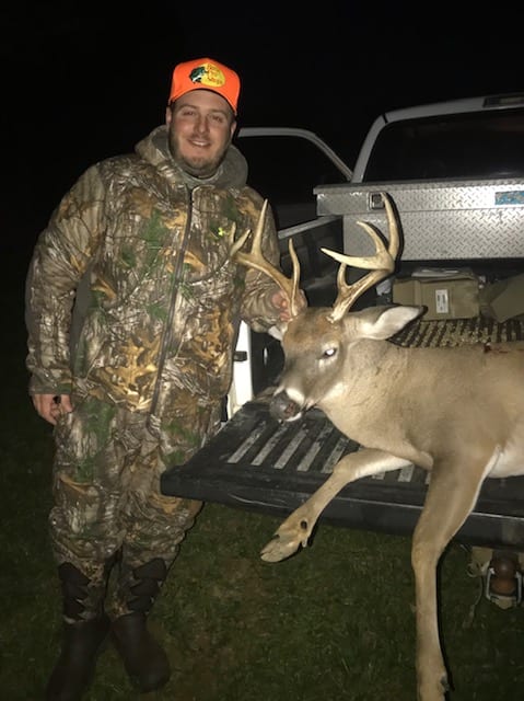 Hunter with whitetail buck on truck tailgate