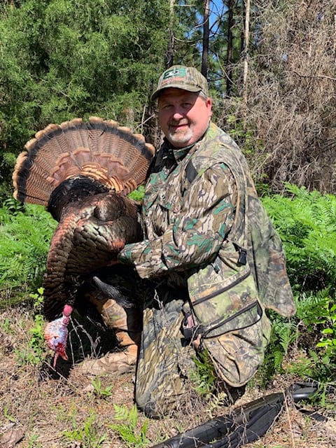 Camouflaged hunter posing with wild turkey