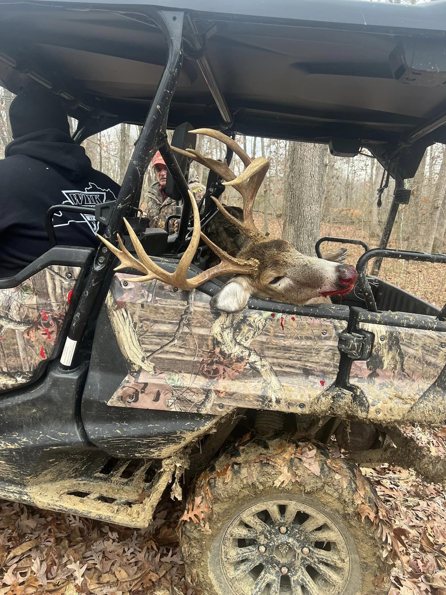 A large buck rests on the open door of a side-by-side UTV during a Kentucky deer hunt.