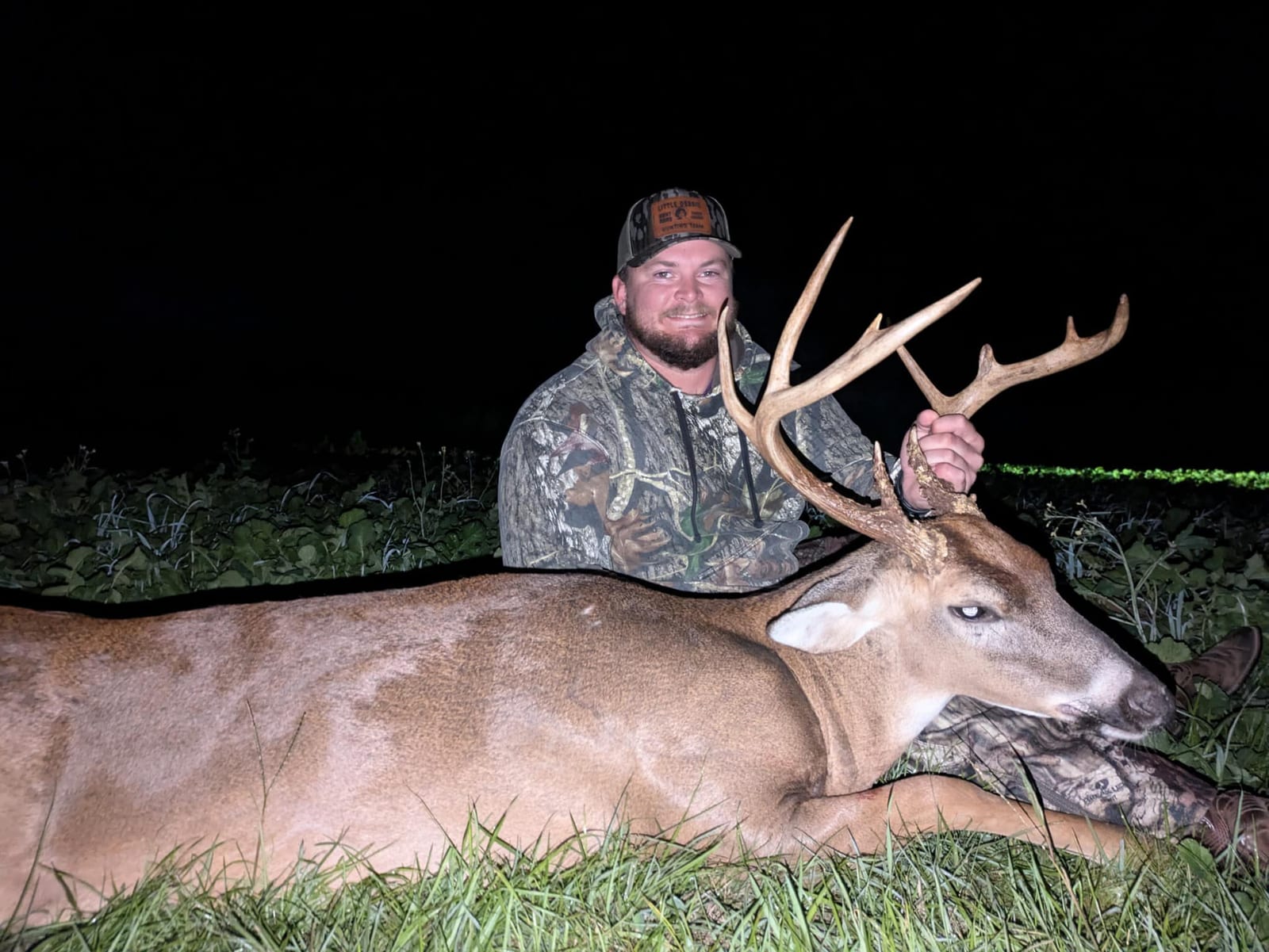 A hunter poses at night with a harvested whitetail deer.